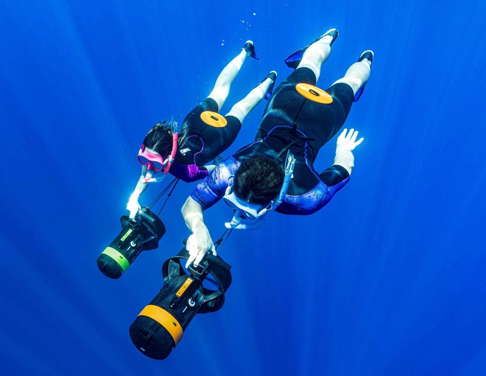 Zwei Apnoetaucher mit einem kompakten SUEX DPV in der Hand tauchen ins blaue Wasser ab