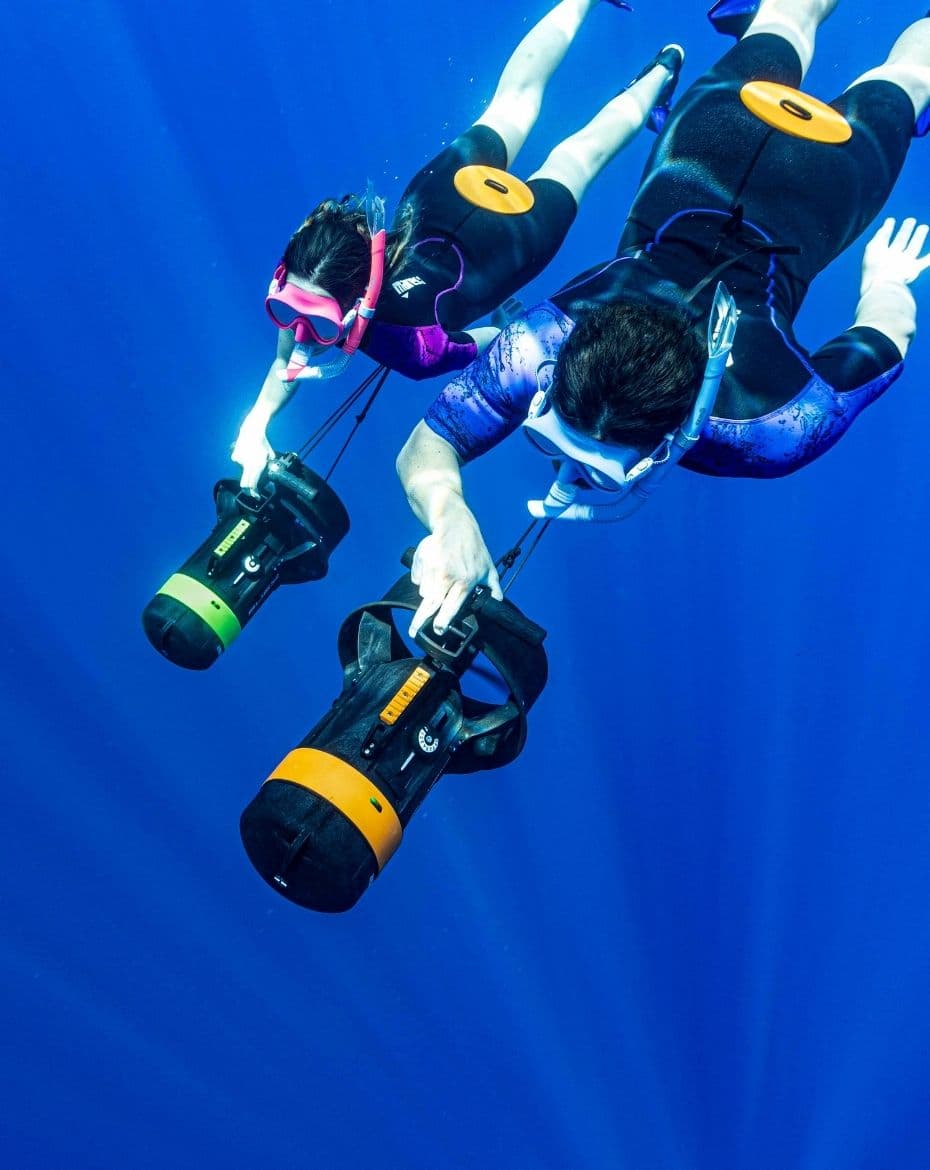 Two freedivers descending, towed by NEMO DPVs