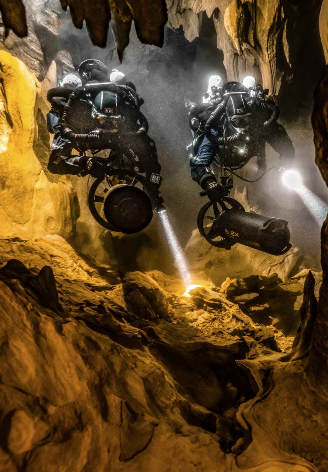 Zwei Taucher mit SUEX DPV erkunden eine überflutete Höhle mit eingeschalteten Lampen