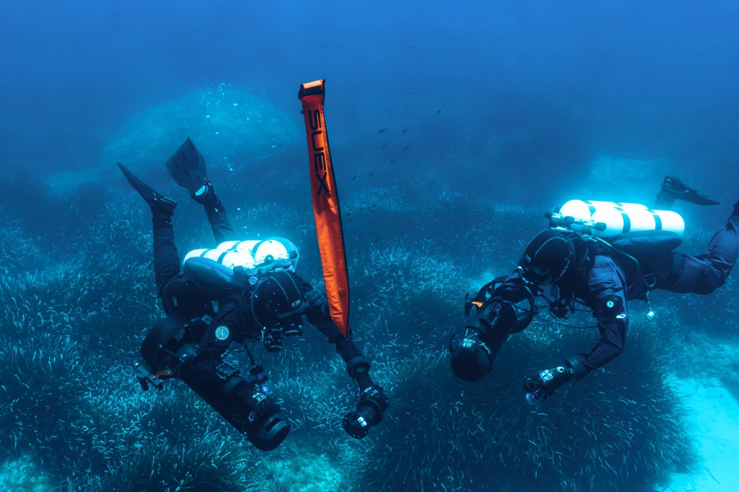 Zwei technische Taucher mit SUEX DPV über einer Posidonia-Wiese, mit einer zur Oberfläche aufgelassenen SUEX Signalboje